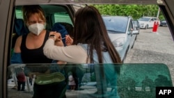 A woman receives a Pfizer/BioNTech vaccination against COVID-19 in a car at a drive-in vaccination center in Pilsen, Czech Republic, May 21, 2021.