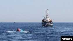 A Vietnamese sinking boat (L), which was rammed and then sunk by Chinese vessels near disputed Paracels Islands, is seen near a Marine Guard ship (R) at Ly Son island of Vietnam's central Quang Ngai province, May 29, 2014.