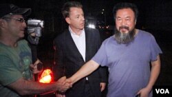 Artis pembangkang Ai Weiwei (kanan) disalami oleh seorang wartawan asing setelah pembebasannya di Beijing (22/6).