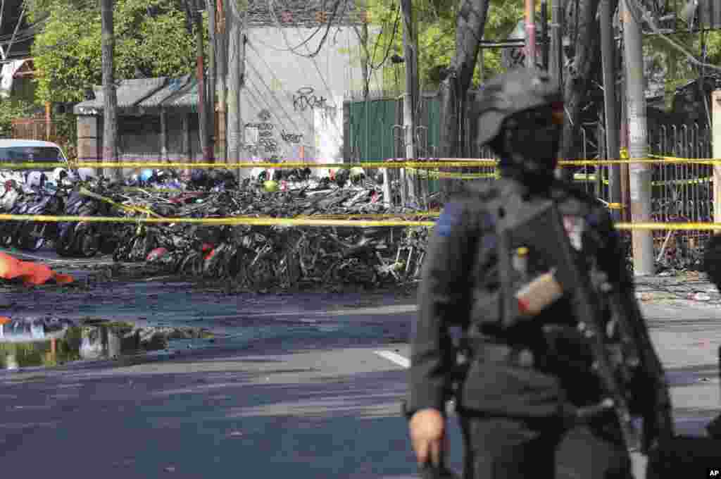 Seorang petugas kepolisian berjaga dekat lokasi terjadinya ledakan di luar sebuah gereja di Surabaya, Jawa Timur, Minggu, 13 Mei 2018. Pelaku menyasar gereja-gereja di kota terbesar kedua di Indonesia, Surabaya, Minggu pagi.