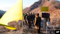 Tentara Korea Selatan, mengenakan helm, bersiap melintasi Garis Demarkasi Militer sementara tentara Korea Utara berdiri di dalam Zona Demiliterisasi (DMZ) di Cheorwon, 12 Desember 2018. (Foto: via AP)