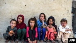 Anak-anak duduk di depan sebuah rumah di desa Deh Qubad di distrik Maiwand, Provinsi Kandahar, Afghanistan, 27 September 2020. (Foto: AFP)