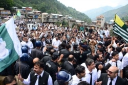 Pakistani police officers try to stop protesters from reaching the Line of Control between Pakistan and Indian Kashmir, at the border town of Chakoti, in Pakistani Kashmir, Thursday, Aug. 29, 2019.