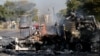 Locals walk past a shell of a burnt out truck used to barricade roads by protesters in Atteridgeville, a township west of Pretoria, South Africa, June 21, 2016.