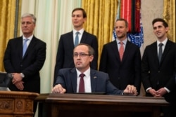 Kosovo Prime Minister Avdullah Hoti, seated, listens as President Donald Trump speaks during a signing ceremony in the Oval Office of the White House, in Washington, Sept. 4, 2020.