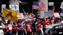 People hold signs and flags during a protest against measures aimed at slowing the spread of the new coronavirus May 1, 2020, in San Diego, California.