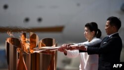 Peraih medali emas Olimpiade tiga kali Jepang Saori Yoshida (kiri) dan Tadahiro Nomura (kanan) menyalakan api Olimpiade Tokyo 2020 dengan obori Olimpiade yang dibawa dari Yunani, di Pangkalan Angkatan Udara Matsushima di Higashimatsushima, Jepang, 20 Maret 2020.