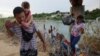 Sejumlah migran dari Venezuela berjalan melewati kawat berduri setelah menyeberangi sungai Rio Grande di Eagle Pass, Texas, pada 26 September 2023. (Foto: Reuters/Brian Snyder)