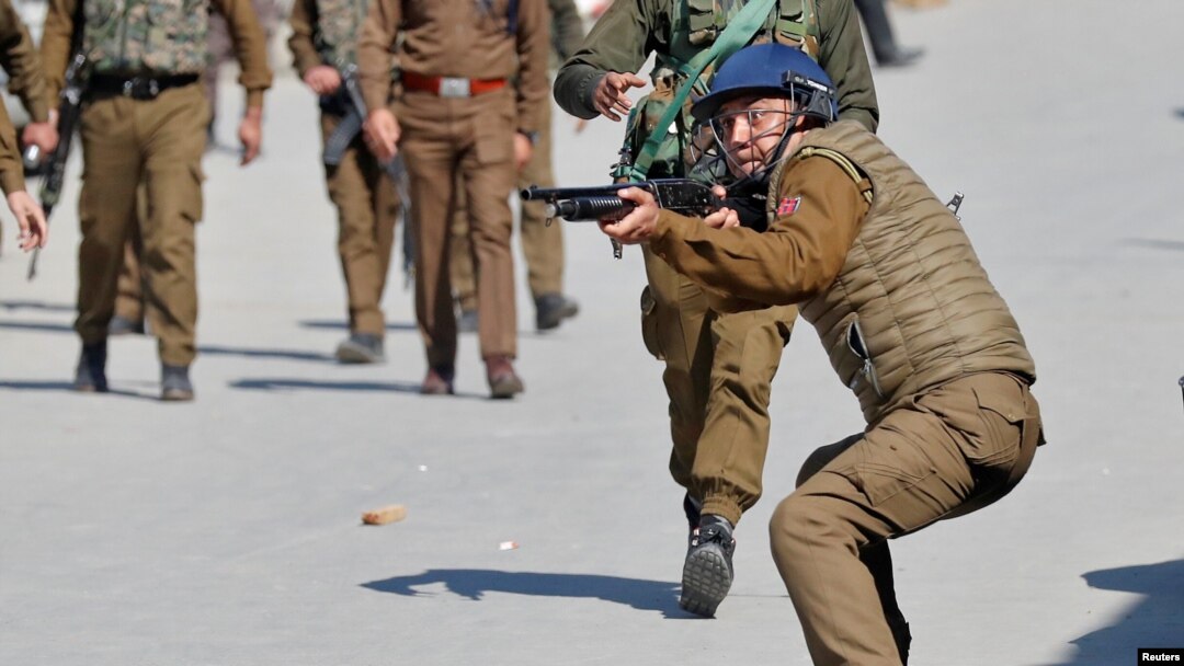 FILE - An Indian police officer aims his pellet gun towards demonstrators during a protest after Friday prayers in Srinagar, March 5, 2021. 