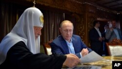 Russian President Vladimir Putin, with Russian Orthodox Patriarch Kirill, left, speak in the library of the Russian monastery St. Panteleimon at Karyes, on Mount Athos, Greece, May 28, 2016.