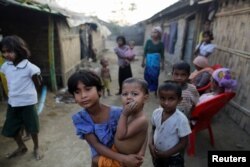 A Rohingya refugee girl carries a baby inside a refugee camp in Sitwe, in the state of Rakhine, Myanmar, March 4, 2017.