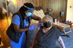 Perawat Alameda County Devette Laflore menyuntikkan vaksin COVID-19 kepada Patti Amaral, 73, di kamar tidur kondominiumnya di Hayward, California, 6 Mei 2021.