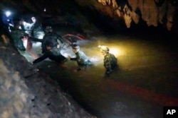 In this handout photo released by Tham Luang Rescue Operation Center, Thai rescue teams walk inside a cave complex where 12 boys and their soccer coach went missing, in Mae Sai, Chiang Rai province, in northern Thailand, July 2, 2018.