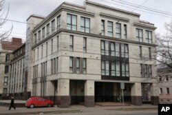 FILE - In this picture taken April 19, 2015, a women enters the four-story building known as the "troll factory" in St. Petersburg, Russia. The “troll factory” is where hundreds of young Russians work around the clock writing blogs and posting comments.