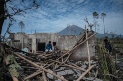 Penduduk desa menyelamatkan barang-barang mereka dari rumah mereka yang rusak di desa Curah Kobokan di Lumajang pada 8 Desember 2021, setelah letusan Gunung Semeru yang menewaskan sedikitnya 34 orang. (Foto: AP)