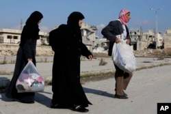 Hamid Malaji returns to his looted home with his wife Amina Hamawy, center and his daughter Radia Malaji, in the Hanano district of eastern Aleppo, Syria, Dec. 4, 2016.