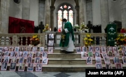 Barisan foto dari perempuan yang meninggal akibat menjadi korban kekerasan terpampang di altar Gereja Katedral di La Paz, Bolivia, pada 25 November 2021, sebagai bagian dari peringatan Hari Anti Kekerasan Terhadap Perempuan. (Foto: AP/Juan Karita)