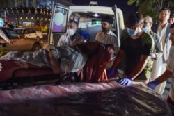 Volunteers and medical staff bring an injured man for treatment after two powerful explosions outside the airport in Kabul, Aug. 26, 2021.