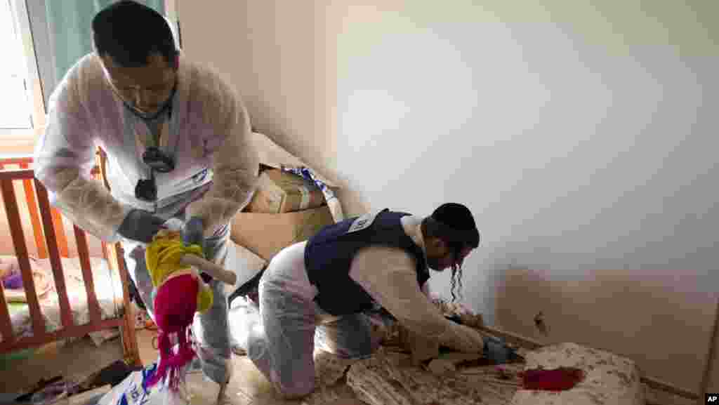 Sukarelawan Zaka membersihkan noda darah di apartemen yang terkena roket di Kiryat Malachi.