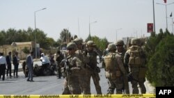 FILE - U.S. soldiers and Afghan security personnel investigate at the site of an attack in Kabul, Afghanistan, Sept. 24, 2017.