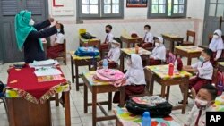 Siswa yang menggunakan masker saat mengikuti pelajaran hari pertama pembukaan kembali sekolah di sebuah sekolah dasar di Jakarta, Senin, 30 Agustus 2021. (Foto: AP)