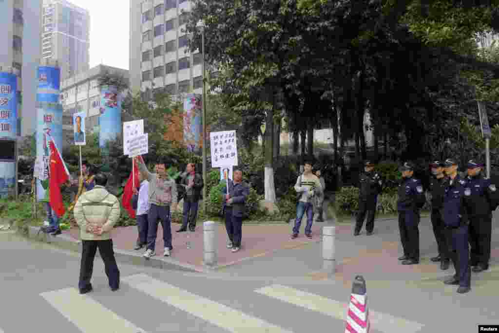 2013年1月8日,示威抗议者在《南方周末》总部外面的执勤警察旁边举着旗帜和已故毛泽东的画像。