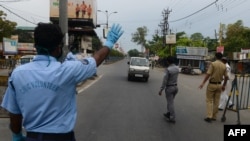 Personel polisi dan sukarelawan sipil menghentikan kendaraan di pos pemeriksaan saat berlangsungnya karantina nasional yang diberlakukan pemerintah sebagai tindakan pencegahan terhadap penyebaran virus COVID-19, di Siliguri, India, 13 April 2020. (Foto oleh DIPTENDU DUTTA / AFP)