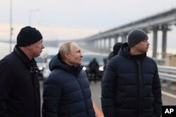 Presiden Rusia Vladimir Putin, tengah, dan Wakil Perdana Menteri Marat Khusnullin, kiri, mengunjungi selesainya perbaikan Jembatan Krimea yang rusak akibat serangan bom truk pada Oktober, 5 Desember 2022. (Foto: via AP)