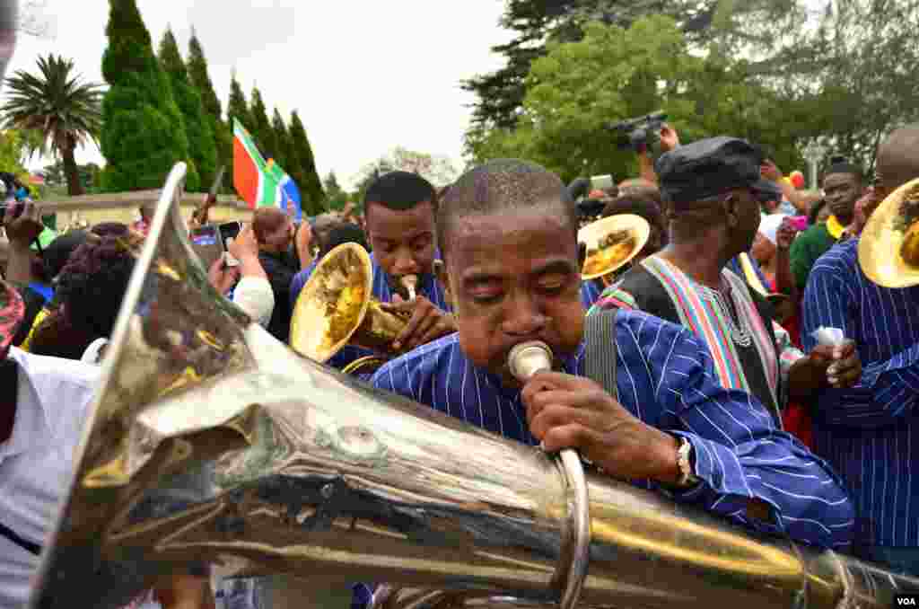 A brass band marches through the streets in front of Nelson Mandela's home in Houghton, Johannesburg, Dec. 9, 2013. (Peter Cox for VOA)
