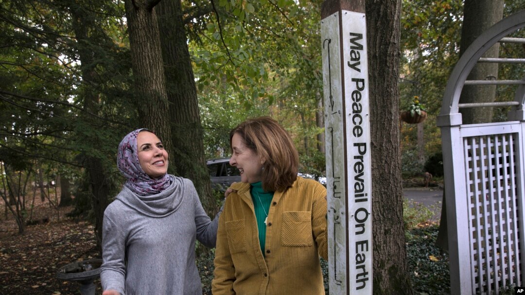 Heba Macksoud, left, of Princeton, New Jersey, and Sheryl Olitzky, members of the Sisterhood of Salaam Shalom, stand near a Peace Pole, with English and Arabic writings, in North Brunswick, New Jersey, Oct. 17, 2019.