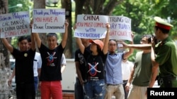 A policeman tries to stop anti-China protesters holding placards during a demonstration in front of the Philippines embassy in Hanoi, Vietnam July 17, 2016.
