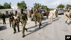 Somali soldiers patrol near the wreckage of a car bomb that was detonated at the main gate of the presidential palace in Mogadishu, Somalia, July, 9, 2014. 