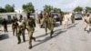 Somali soldiers patrol near the wreckage of a car bomb that was detonated at the main gate of the presidential palace in Mogadishu, Somalia, July, 9, 2014. 