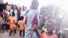 A child stands in floodwaters at a camp for people displaced by violence, Bentiu, South Sudan (G. Joselow/VOA).