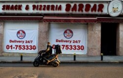 A food delivery scooter passes Barbar Restaurant that now offers food for delivery only, after most of the shops and restaurants closed, Beirut, March 21, 2020.