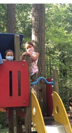 Dua anak kakak-beradik tetap mengenakan masker ketika bermain di sebuah taman bermain di Maryland (foto: courtesy).