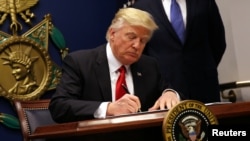 US President Donald Trump signs an executive order to impose tighter vetting of travelers entering the United States, at the Pentagon in Washington, Jan. 27, 2017.