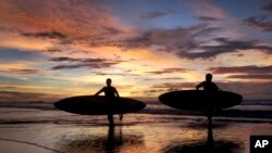 Dua peselancar di pantai di Bali.
