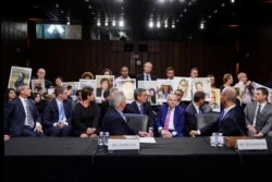 John Hamilton, Wakil Presiden Boeing Commercial Airplanes, dan CEO Boeing Dennis Muilenburg melihat ke arah anggota keluarga korban kecelakaan Boeing 737 MAX yang memegang foto anggota keluarga, di Senat AS, 30 Oktober 2019.