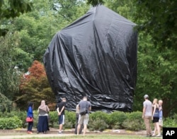 Residents and visitors look over the covered statue of Confederate General Robert E. Lee in Emancipation park in Charlottesville, Va., Aug. 23, 2017. The move to cover the statues is intended to symbolize the city's mourning for Heather Heyer, killed while protesting a white nationalist rally.