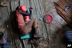 FILE - A Koranic student sleeps with his begging bowl covering his face in the unfinished first floor of a building which serves as both classroom and living space for the dozens of students at his school in Dakar, Senegal, Aug. 31, 2010.