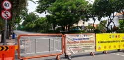 Jalan Raya Darmo di Surabaya ditutup untuk mengurangi mobilitas warga dan kendaraan di jalan itu, 4 April 2020. (Foto: Petrus Riski/VOA)