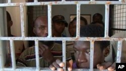 FILE - African migrants look through bars of a locked door at Sabratha migrant detention center for men in Sabratha, Libya, October 2013.