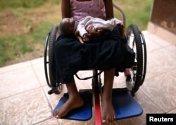 FILE - A five-year-old girl poses with her doll as she sits in her wheelchair in the courtyard of the Aberdeen Women's Center, one year after a sexual assault that her family says left her paralyzed, in Freetown, Sierra Leone, Feb. 7, 2019.