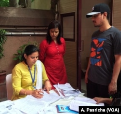 Voters wait as election officers search for their names at a polling booth in New Delhi.