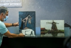 Lukisan "Head of a Woman" Pablo Picasso dan "Mill" Piet Mondrian, keduanya dicuri dari Galeri Nasional Yunani pada 2012, di Kementerian Perlindungan Warga di Athena, Yunani, 29 Juni 2021. (REUTERS/Costas Baltas)