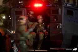 FILE - U.S. law enforcement agents board a truck to conduct an early morning raid against members and associates of the MS-13 gang, May 17, 2017, in Los Angeles, California. MS-13 has morphed into one of the largest and most violent gangs in the United States, boasting an estimated 10,000 members.