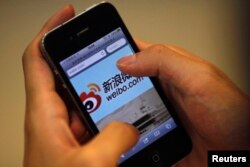 Seorang pria memegang iPhone saat ia mengunjungi situs microblogging Weibo Sina di Shanghai, 29 Mei 2012. (Foto: Reuters)
