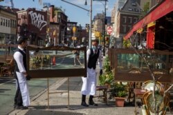 Para pelayan di sebuah restoran di New York, mengatur jarak sosial tempat duduk di luar ruangan untuk mengikuti protokol kesehatan di tengah pandemi Covid-19, AS, 25 Juni 2020.