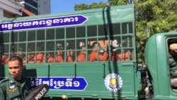 Aktivis pemuda Kung Raiya melambaikan tangannya saat sebuah van membawanya bersama dengan tahanan lain dari penjara Prey Sar ke Pengadilan Kota Phnom Penh, di Phnom Penh, 26 November 2019. (Hul Reaksmey / VOA Khmer)